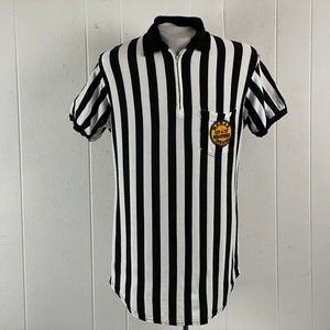 May include: Black and white striped referee shirt with a yellow patch that says "1974-75 Washington Officials".