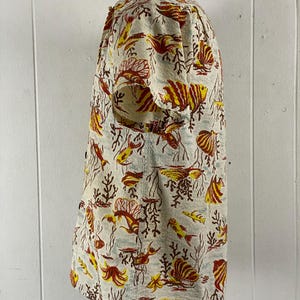 May include: A short-sleeved button-up shirt with a white background and a colorful pattern of red, yellow, and orange fish and coral.