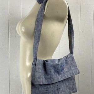 May include: A blue and white striped fabric crossbody bag with a long strap. The strap is tied into a bow at the top of the bag.
