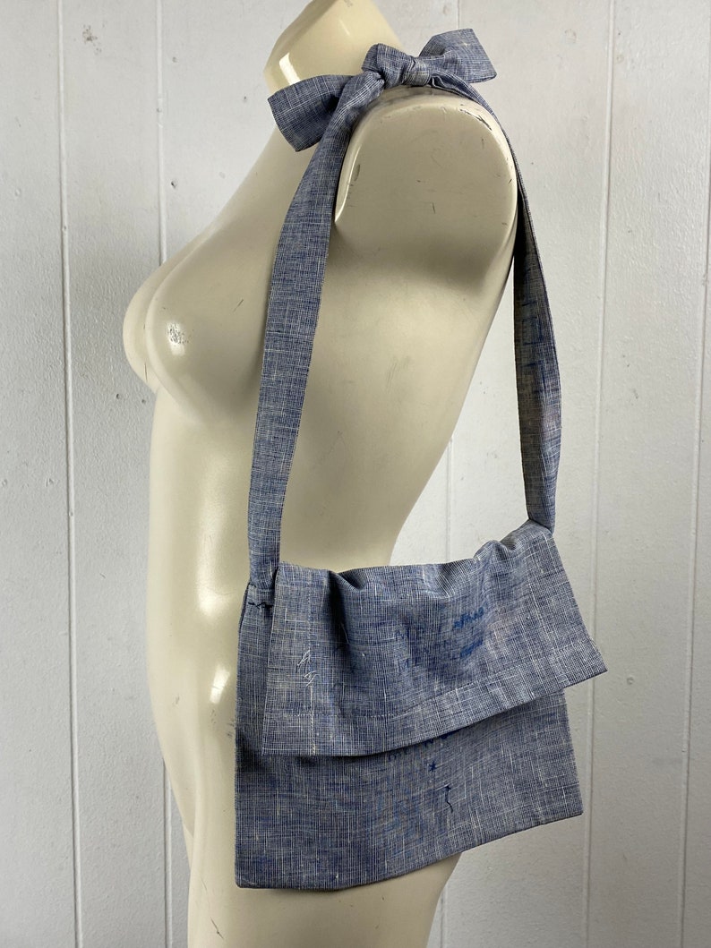 May include: A blue and white striped fabric crossbody bag with a long strap. The strap is tied into a bow at the top of the bag.