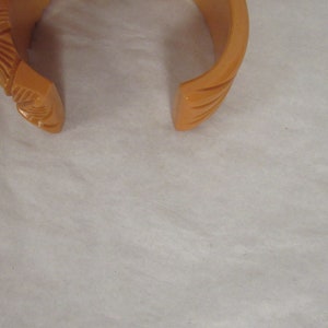 Puede incluir: Un brazalete vintage de pl&aacute;stico naranja con un dise&ntilde;o tallado.