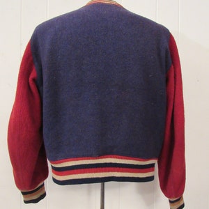 May include: A navy blue and red varsity jacket with a ribbed knit collar, cuffs, and waistband. The jacket has a white, red, and navy blue striped trim.