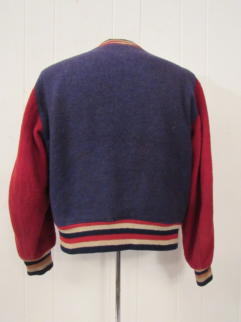 May include: A navy blue and red varsity jacket with a ribbed knit collar, cuffs, and waistband. The jacket has a white, red, and navy blue striped trim.