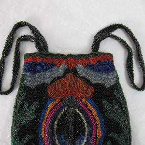 Puede incluir: Un bolso de noche de cuentas con fondo negro y dise&ntilde;os geom&eacute;tricos coloridos. El bolso tiene dos correas de cuentas negras.