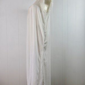 Puede incluir: Un camis&oacute;n blanco de algod&oacute;n con un ribete de encaje alrededor del cuello y las mangas. El camis&oacute;n es largo y fluido, y se muestra en un maniqu&iacute;.