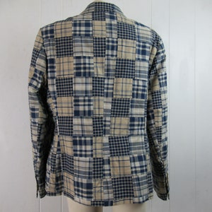 May include: A blue and beige plaid blazer with a patchwork design. The blazer has a button-up front and long sleeves.