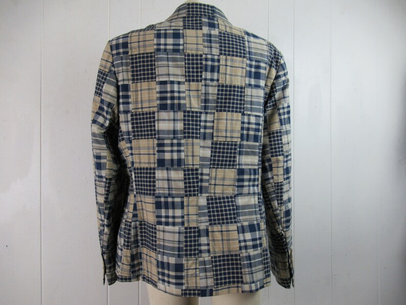 May include: A blue and beige plaid blazer with a patchwork design. The blazer has a button-up front and long sleeves.