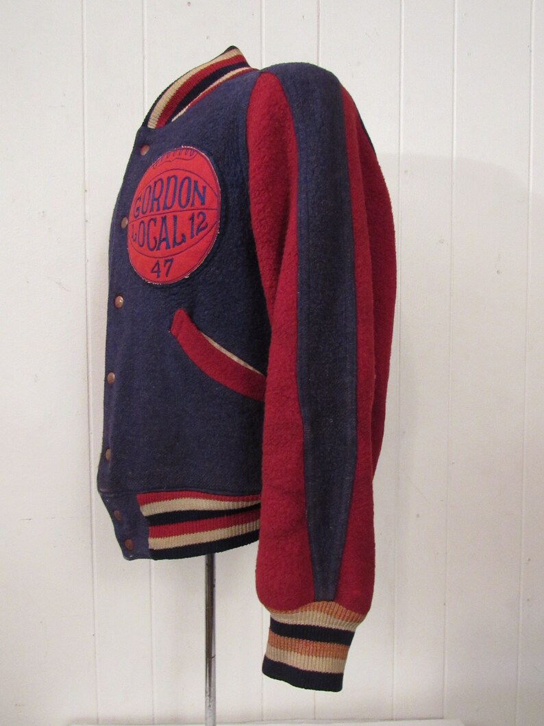 May include: A vintage blue and red varsity jacket with a white and black striped cuff. The jacket has a large circular patch on the left chest with the text "Gordon Local 12" and the number "47" underneath.