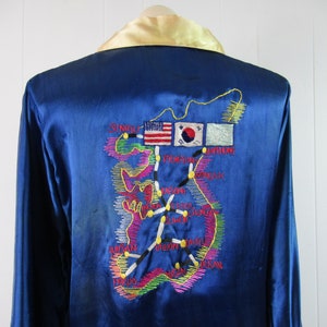 May include: A blue satin robe with an embroidered map of South Korea on the back. The map includes the names of cities and the flags of the United States and South Korea.