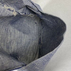 May include: Close-up of the inside of a blue and white checkered fabric. The fabric is folded in half and the edges are frayed.