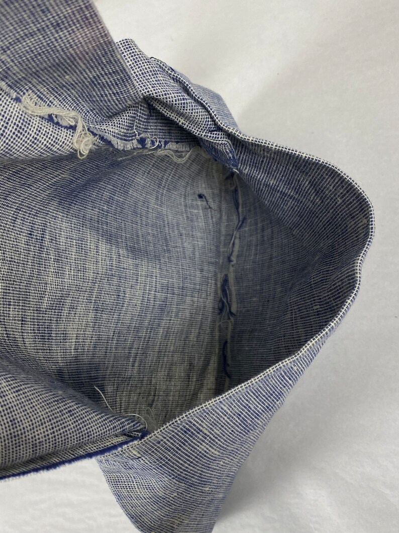 May include: Close-up of the inside of a blue and white checkered fabric. The fabric is folded in half and the edges are frayed.