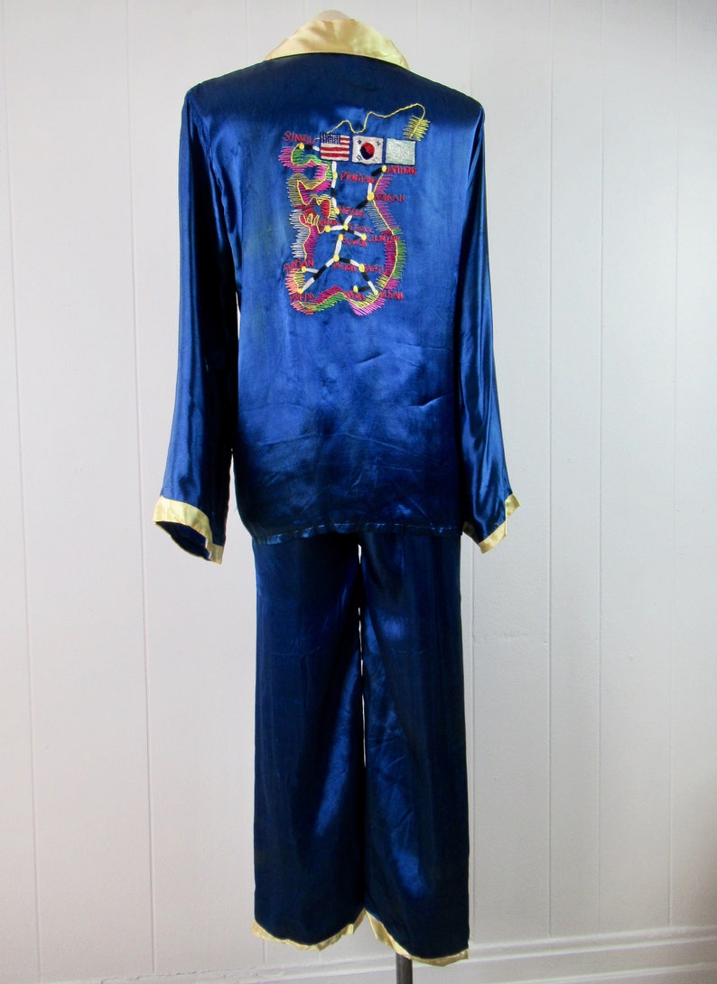 May include: Blue satin pajamas with a map of Korea embroidered on the back. The map includes flags of South Korea, the United States, and the United Nations.