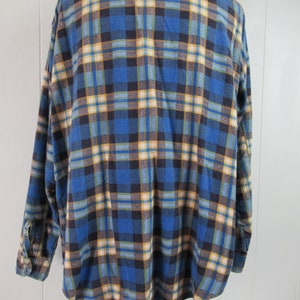 以下が含まれることがあります： 長袖でボタン留めの青い、黄色、茶色の格子柄のフランネルシャツです。