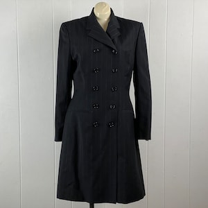 May include: A black pinstripe double-breasted coat with a long, fitted silhouette. The coat has a pointed collar and six black buttons down the front.