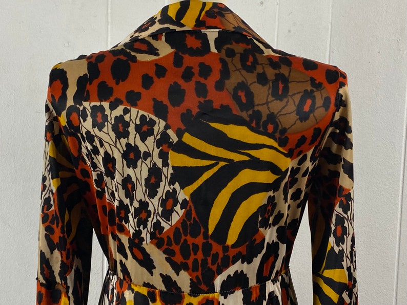 Puede incluir: Una bata de manga larga con cuello, con un dise&ntilde;o estampado en marr&oacute;n, negro, amarillo y blanco.