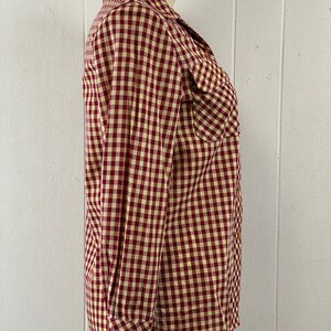 May include: A red and white gingham long-sleeved button-up shirt with a pointed collar and two chest pockets.