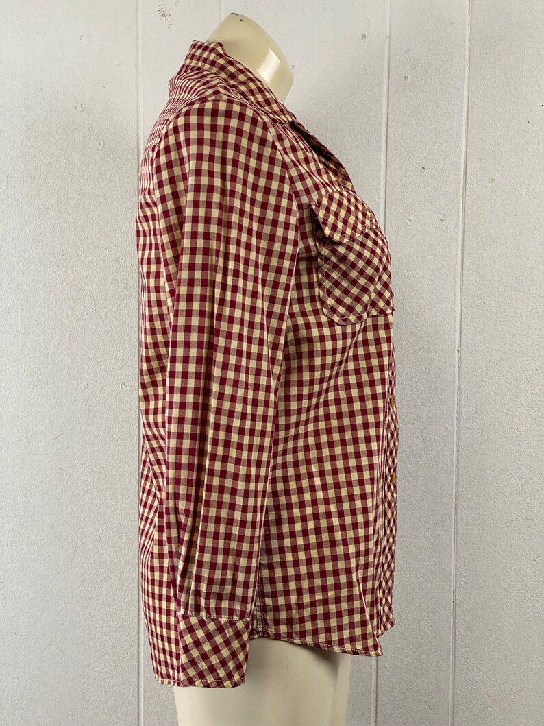 May include: A red and white gingham long-sleeved button-up shirt with a pointed collar and two chest pockets.