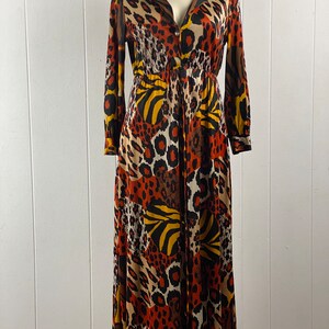 Puede incluir: Un vestido largo de manga larga con cierre de botones en la parte delantera y un estampado de animales de colores. El vestido est&aacute; hecho de una tela suave y fluida y tiene un corte holgado.