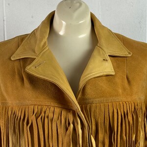 Puede incluir: Una chaqueta de ante marr&oacute;n con detalles de flecos. La chaqueta tiene cuello y cierre de bot&oacute;n.