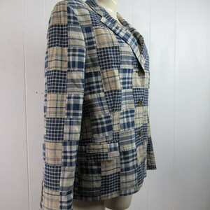 May include: A blue and beige plaid blazer with a patchwork design. The blazer has a notched collar, two button closure, and two flap pockets.