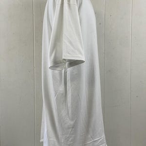 May include: A white, short-sleeved t-shirt. The shirt is made of a soft, lightweight fabric and has a relaxed fit. The sleeves are short and wide, and the hemline is straight. The shirt is displayed on a mannequin.
