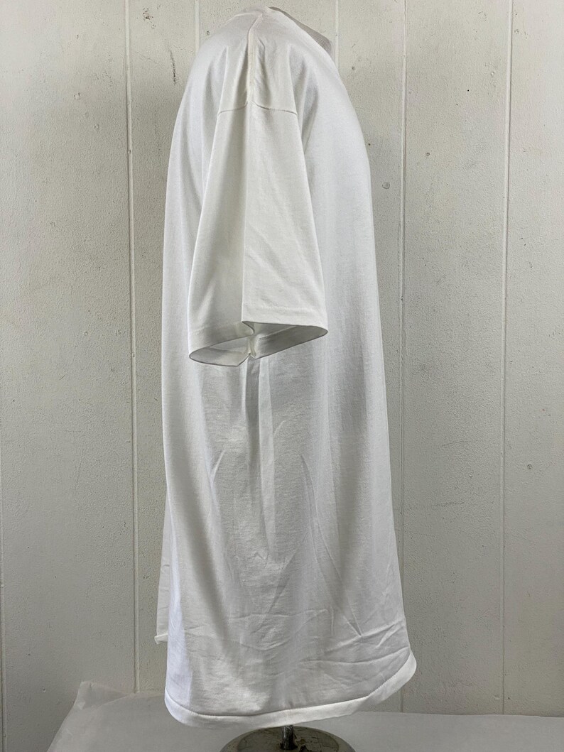 May include: A white, short-sleeved t-shirt. The shirt is made of a soft, lightweight fabric and has a relaxed fit. The sleeves are short and wide, and the hemline is straight. The shirt is displayed on a mannequin.