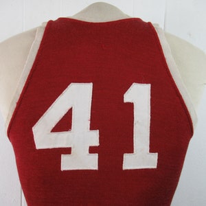 May include: Red basketball jersey with white trim and the number 41 on the back.
