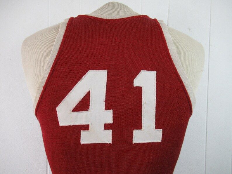 May include: Red basketball jersey with white trim and the number 41 on the back.