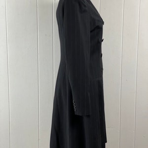 May include: A black pinstripe long-sleeved coat with a double-breasted closure and a flared skirt.