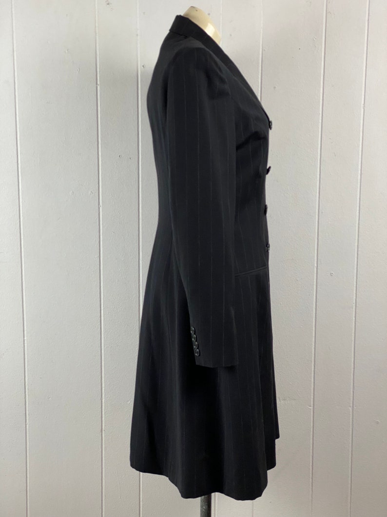 May include: A black pinstripe long-sleeved coat with a double-breasted closure and a flared skirt.