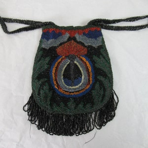 Puede incluir: Un bolso de cuentas negras con un fondo de flecos. El bolso tiene un dise&ntilde;o colorido con cuentas verdes, azules, rojas y naranjas.