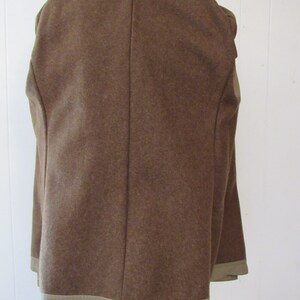 May include: A brown wool jacket with a tan lining. The jacket has a single back seam and a tan trim around the bottom.