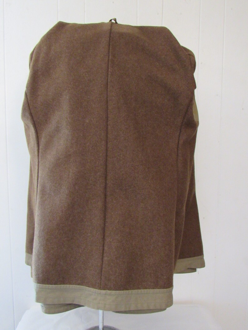 May include: A brown wool jacket with a tan lining. The jacket has a single back seam and a tan trim around the bottom.