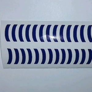 Puede incluir: Una hoja de papel adhesivo blanco con 12 formas de media luna azul oscuro.