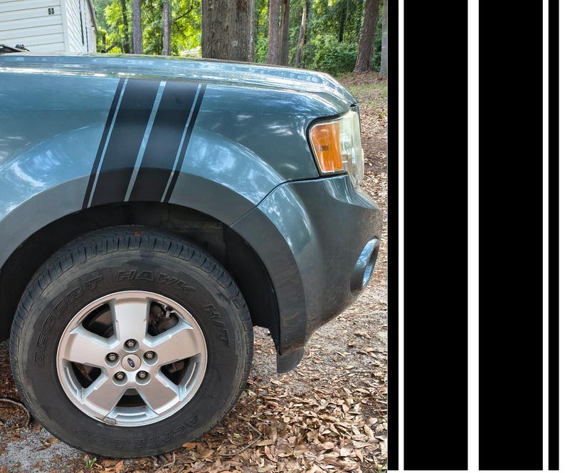 May include: A teal car fender with black racing stripes. The car has a silver wheel with a black tyre. The background includes trees and a house.