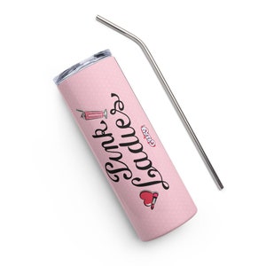 Puede incluir: Un vaso térmico de acero inoxidable rosa con un patrón de lunares blancos y el texto "Pink Ladies" en cursiva negra. El vaso tiene un corazón rojo con un gráfico de lápiz labial y un gráfico de batido rosa. El vaso viene con una pajita de metal plateada.