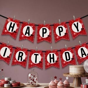 Puede incluir: Una festiva pancarta de cumpleaños con banderas rojas brillantes que deletrean "HAPPY BIRTHDAY" en letras blancas. La escena incluye globos, un pastel, cupcakes y macarons, creando un ambiente festivo. La pancarta está colgada sobre un fondo oscuro.