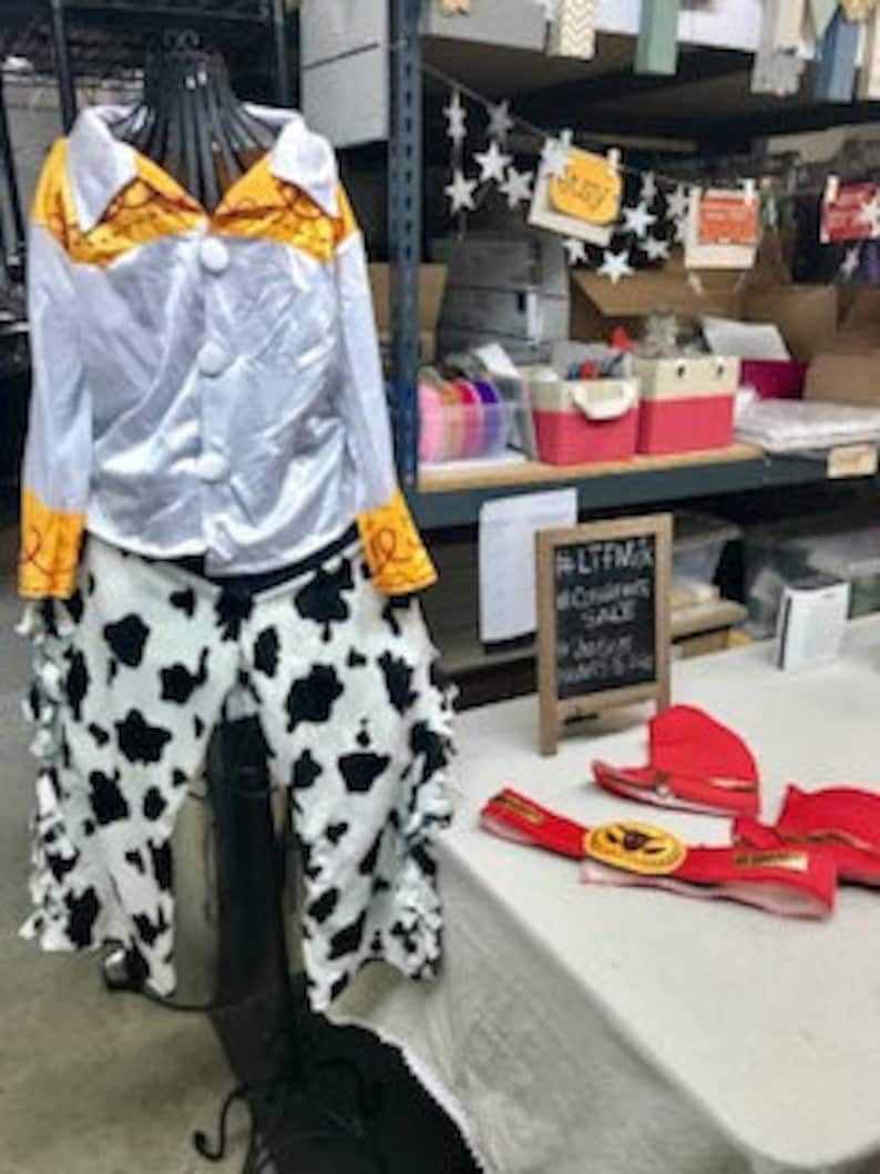 Puede incluir: Un pantal&oacute;n de estampado de vaca blanco y negro y una camisa de sat&eacute;n blanco con detalles amarillos, un disfraz de vaquero para ni&ntilde;os.