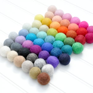 K&ouml;nnte beinhalten: Eine Regenbogen-Sortiment an Filzkugeln, die in Pyramidenform angeordnet sind. Die Kugeln sind in verschiedenen Farben, darunter Rot, Orange, Gelb, Gr&uuml;n, Blau, Lila, Rosa und Braun.