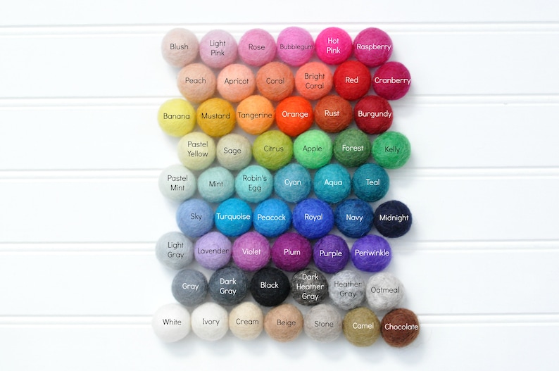 K&ouml;nnte beinhalten: Eine Farbkarte mit 42 Filzkugeln, jede in einer anderen Farbe und mit einem anderen Namen. Die Farben sind in einem Regenbogenmuster angeordnet, beginnend mit Rot und endend mit Lila. Die Namen der Farben sind in schwarzer Schrift auf den Kugeln aufgedruckt.