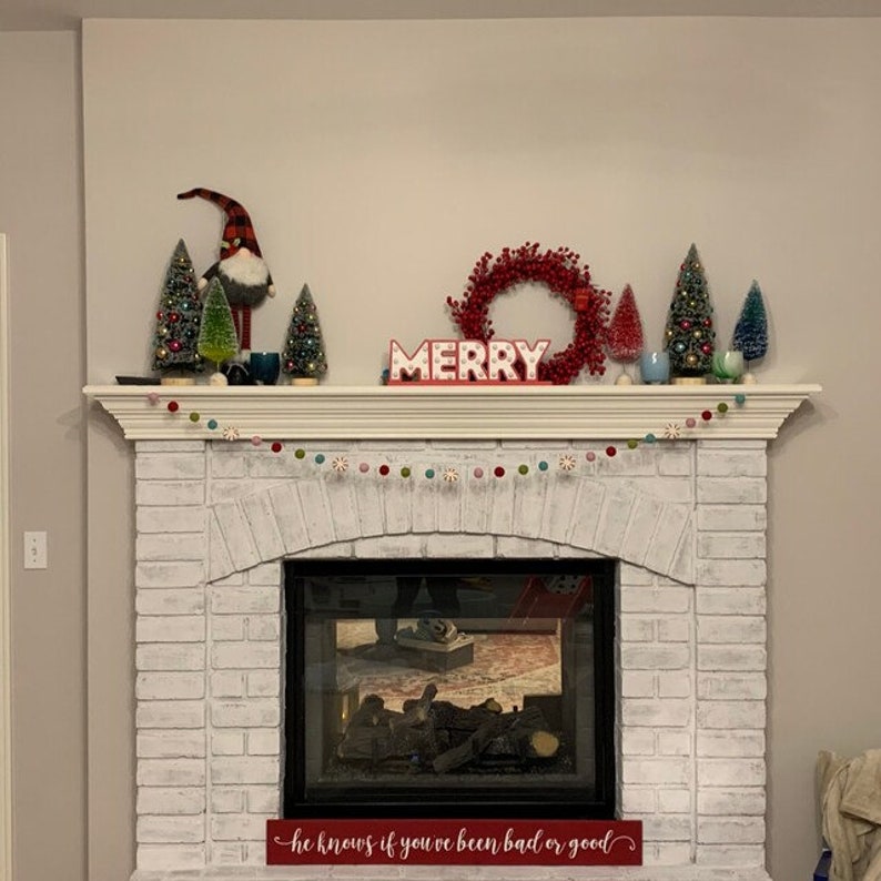 Felt peppermint garland with light pink, red, green, and aqua wool balls on a Christmas mantel display