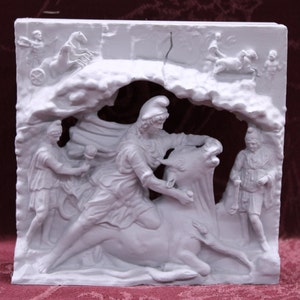 May include: A white plaster relief sculpture depicting a scene from Greek mythology. A man is riding a bull, while another man holds a rope. The sculpture is set against a background of a cave and a rocky landscape.
