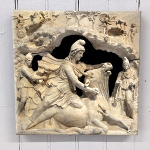 May include: A white marble relief sculpture depicting a scene from Greek mythology. A woman, possibly a goddess, rides a bull, while a man stands behind her, holding a rope. The sculpture is set against a background of carved foliage and other figures.