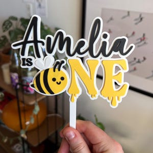 Custom name bee 1st birthday cake topper for girl with floral and honeybee details, perfect for sweet as can bee party theme
