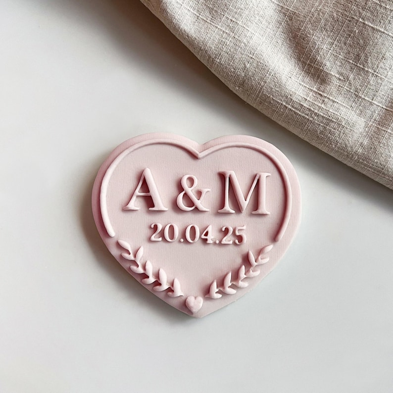 Plastic cookie cutter and fondant stamp with a custom design of wedding initials, made of durable plastic and shown on a white countertop.