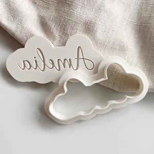 Plastic cookie cutter and fondant stamp with a custom design of a name in script font, made of durable plastic and shown on a white countertop.