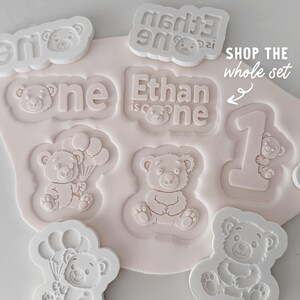 Bear cookie cutter and fondant stamp. Shown on a flat surface.