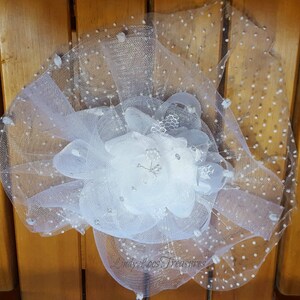 Op de afbeelding: Witte tule bloem met zilveren glitteraccenten. De tule heeft een gestippeld patroon.