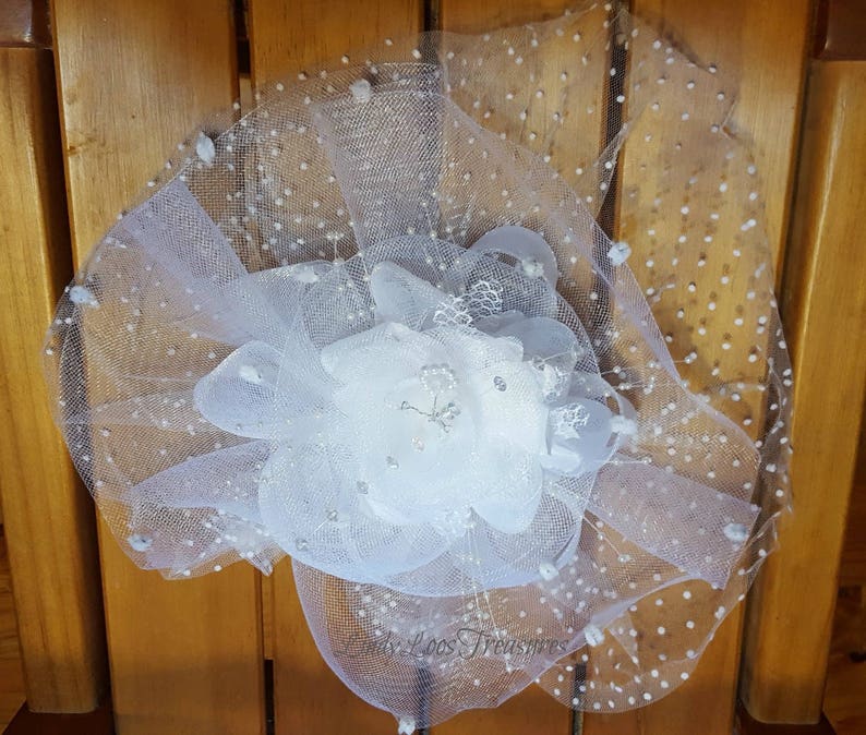 Op de afbeelding: Witte tule bloem met zilveren glitteraccenten. De tule heeft een gestippeld patroon.