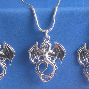 Op de afbeelding: Zilveren draken hanger ketting en oorbellen set. De draak staat met zijn vleugels uitgespreid.